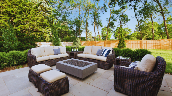 Patio with wicker furniture, fire pit, and lush greenery.