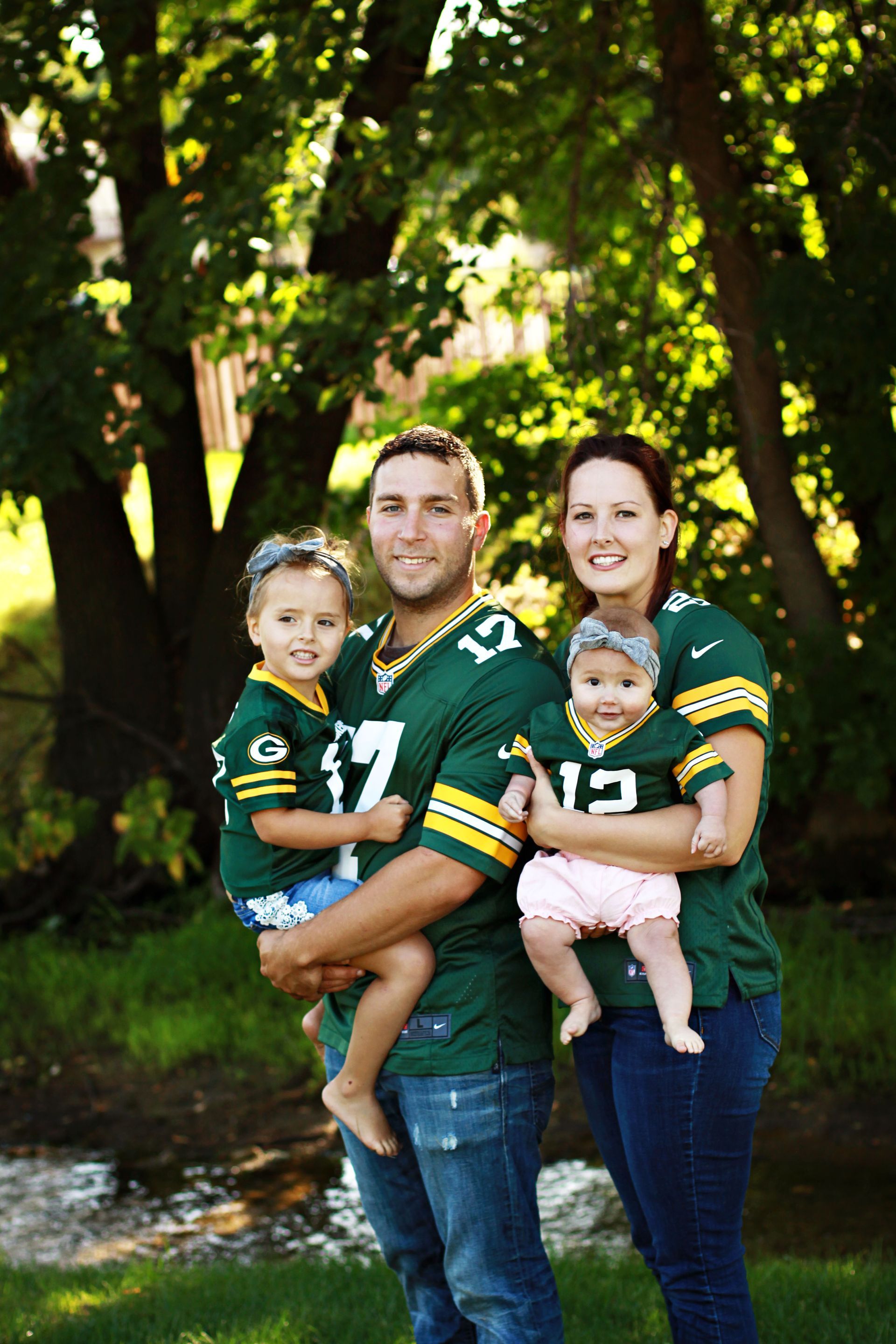 A family is posing for a picture while wearing green bay packers jerseys.