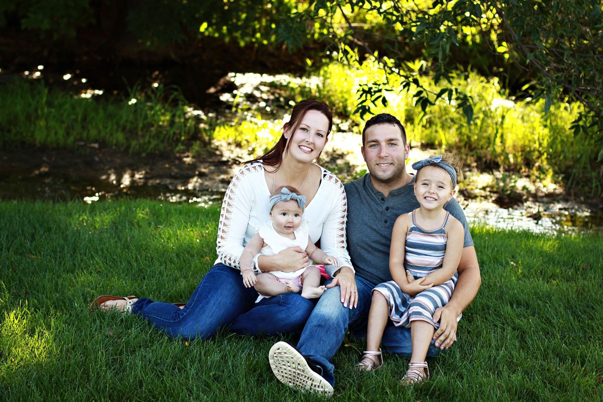 A family is posing for a picture while sitting on the grass.