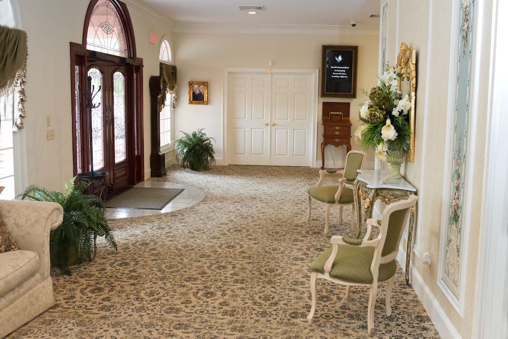 Foyer with a patterned carpet, ornate chairs, and double doors.