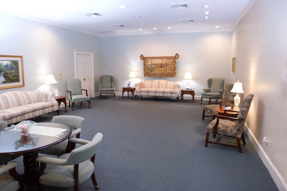 Foyer with a patterned carpet, ornate chairs, and double doors.