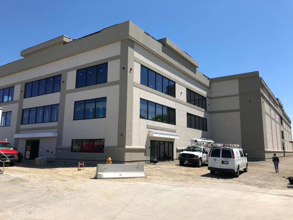 A white van is parked in front of a large building