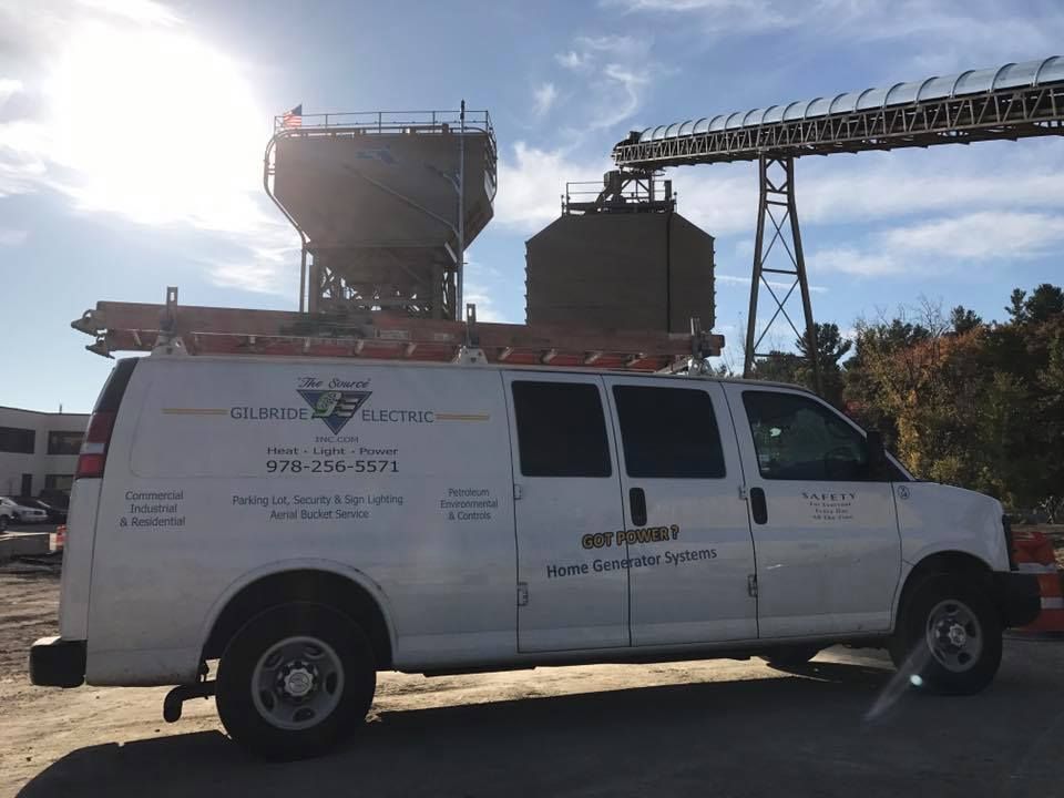 A white van is parked in front of a large building.