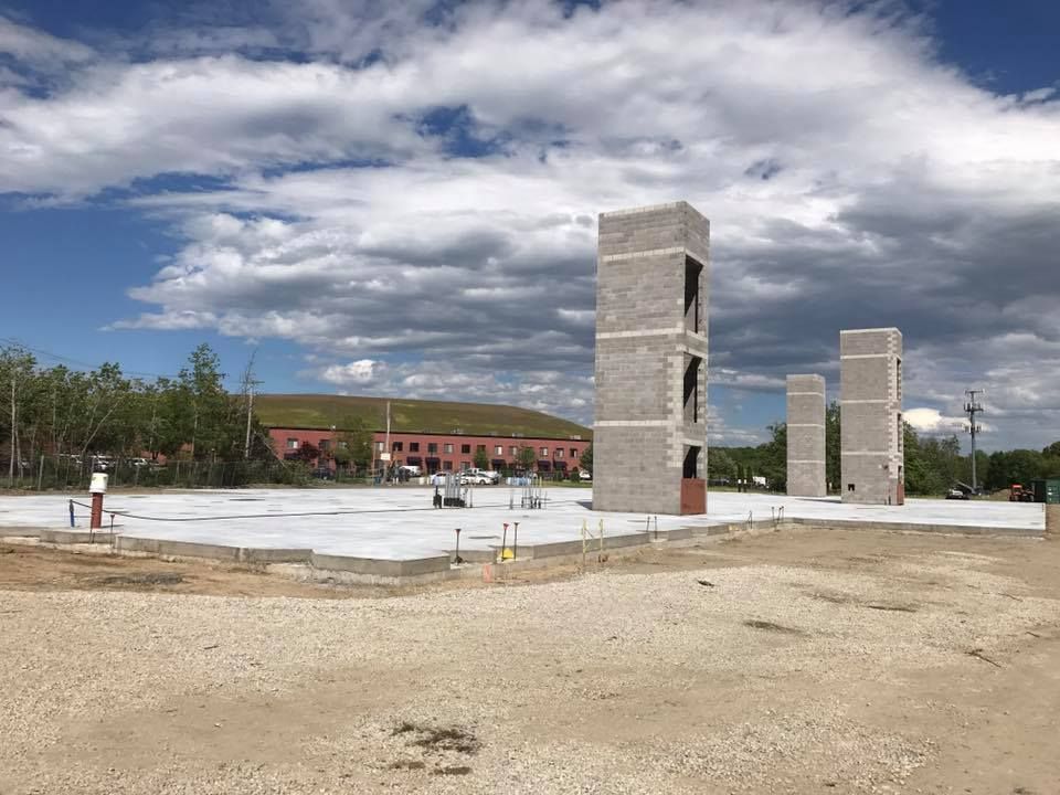 A large concrete structure is being built in the middle of a dirt field.