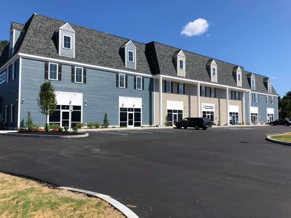 A large blue building with a black truck parked in front of it.