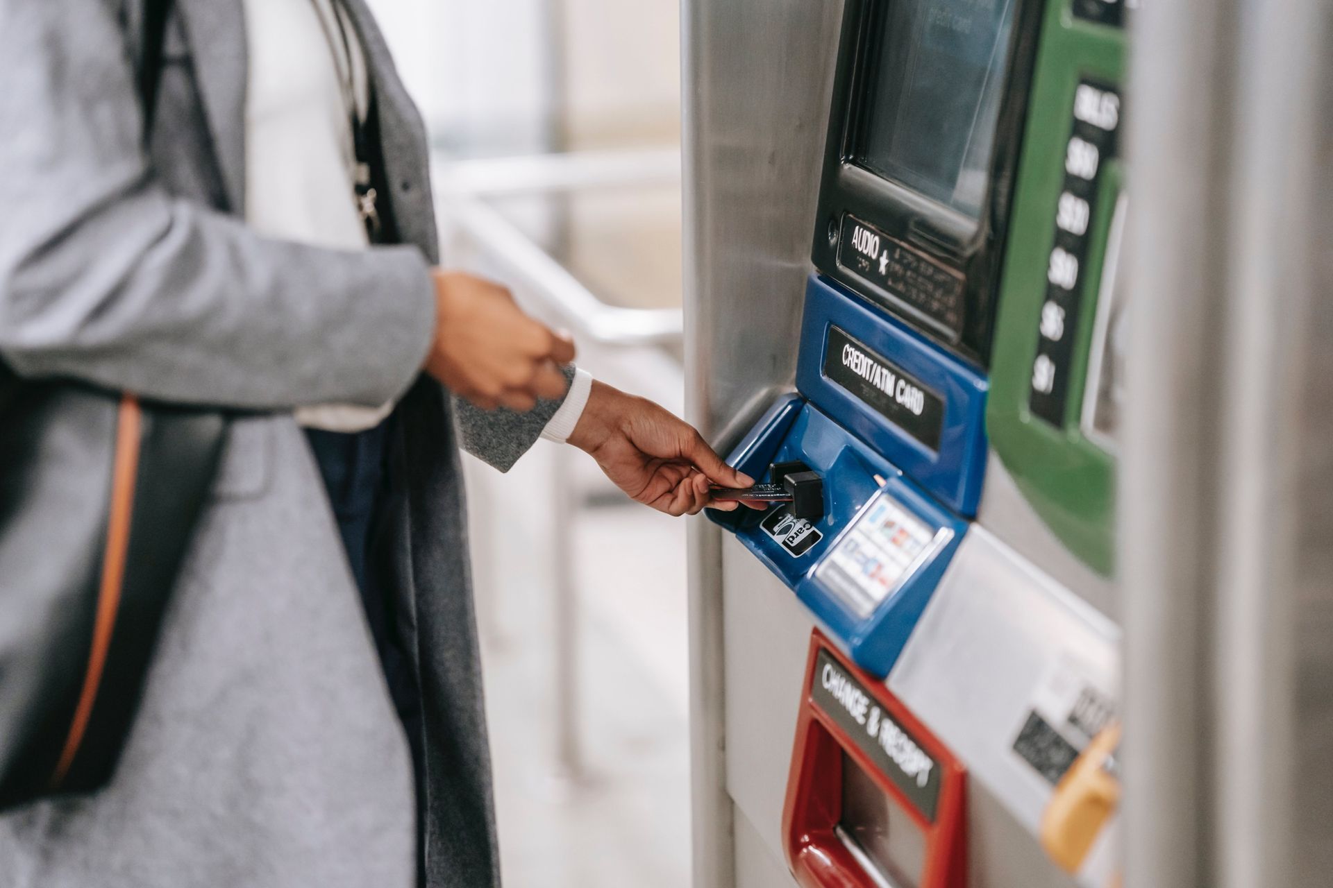 A woman is inserting a credit card into an atm machine.