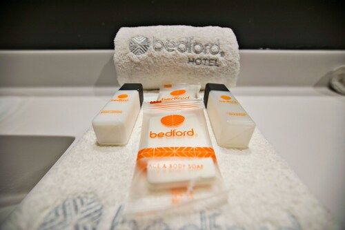 Artículos de aseo del baño del Hotel Bedford: toalla blanca doblada, jabón y botellas de champú y acondicionador.
