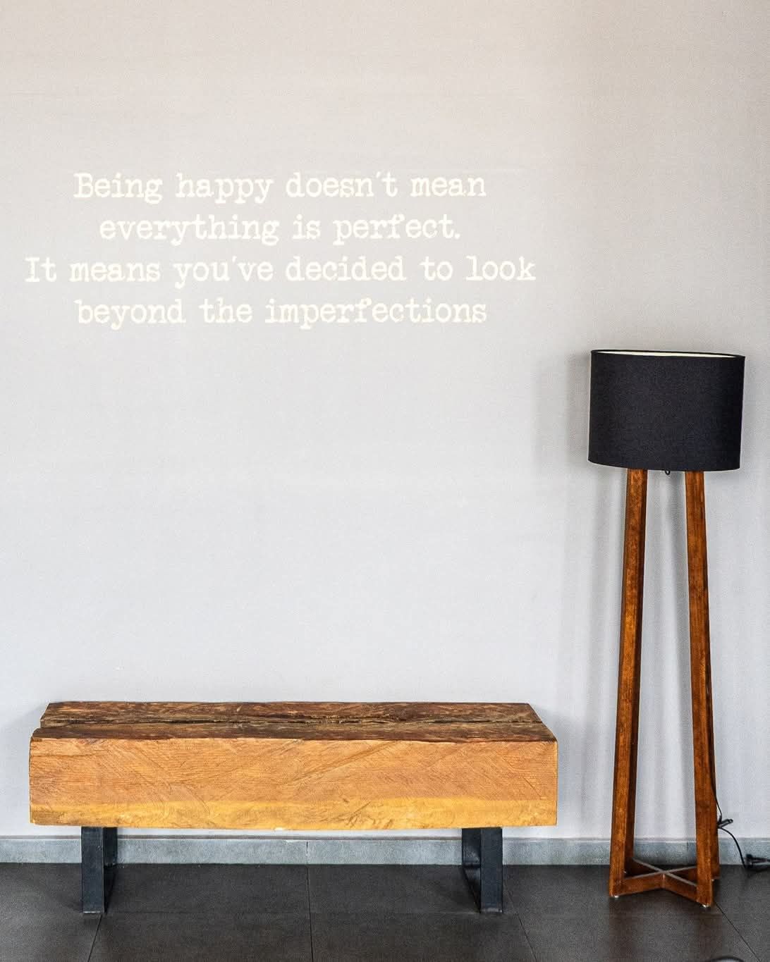 Un banco y una lámpara debajo de una cita en la pared: 