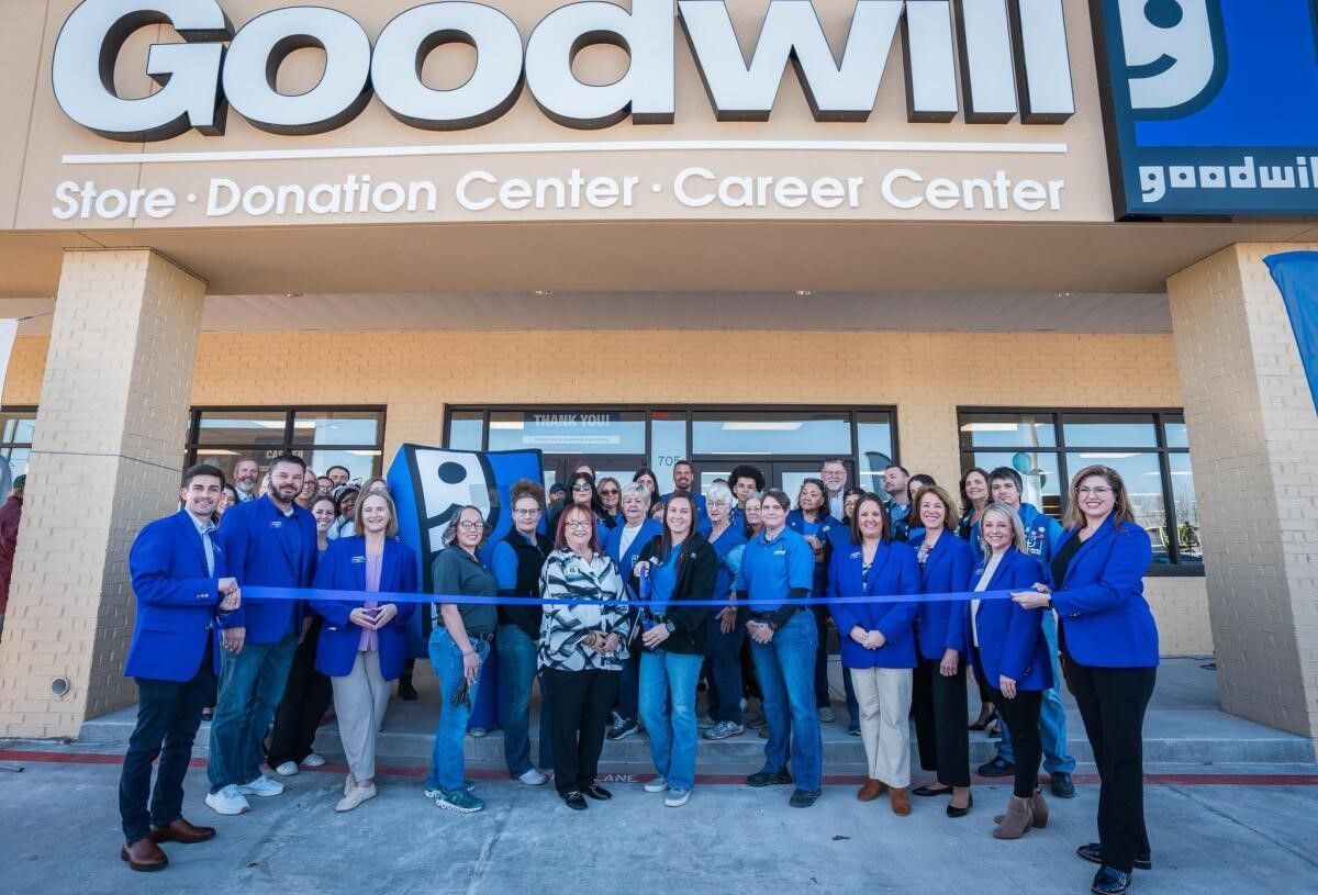 a group of people are standing in front of a goodwill store