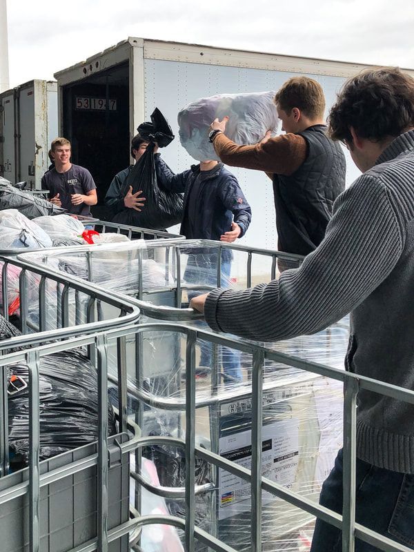 a group of men are loading clothes into a truck .