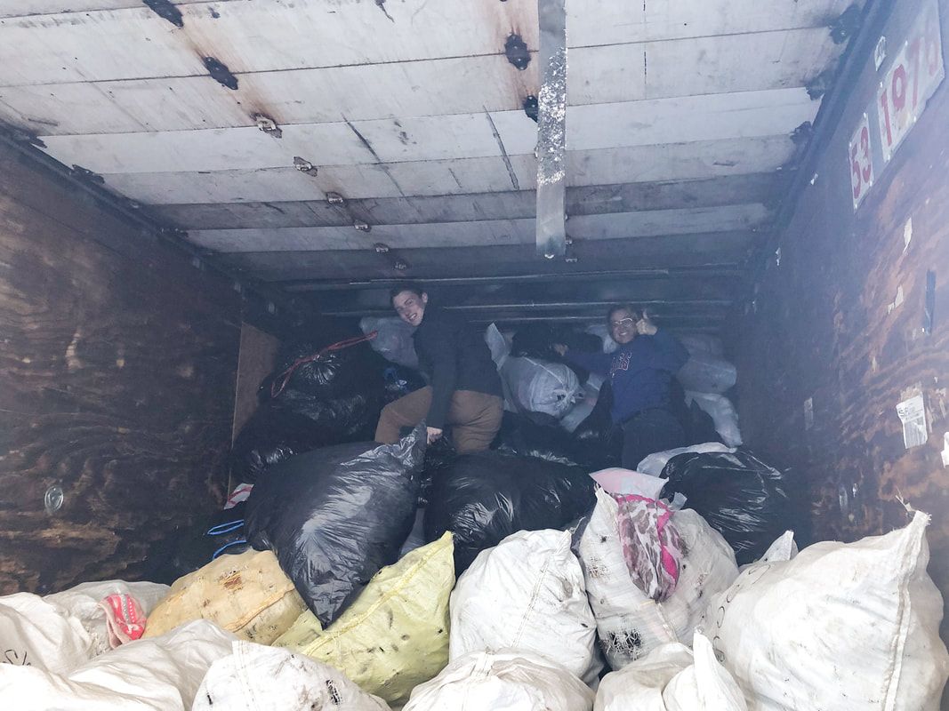 a man is standing in a trash can filled with bags of trash .