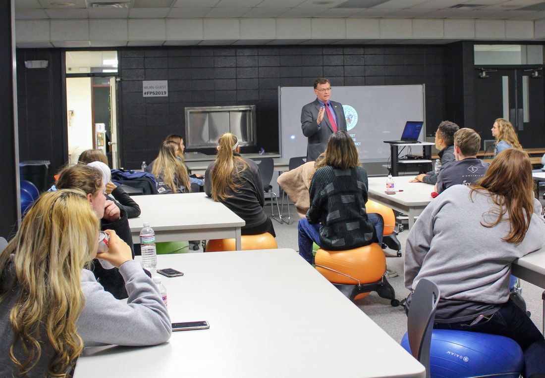 a man is giving a presentation to a group of people in a classroom .