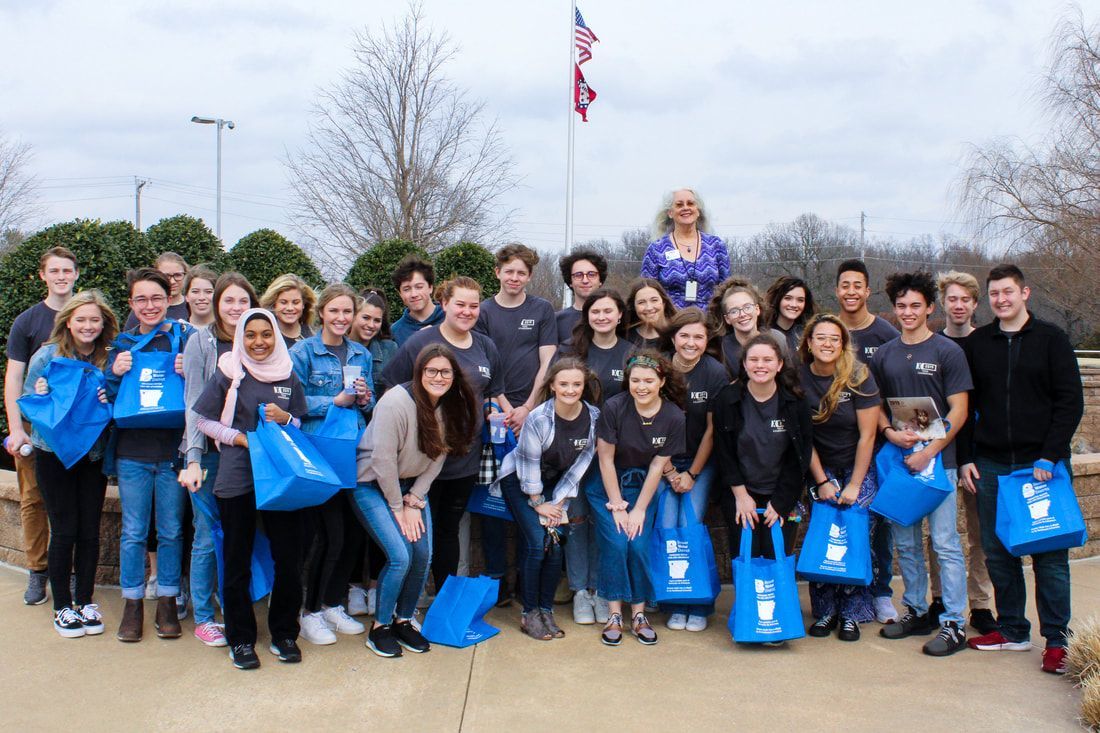 a large group of people are posing for a picture in front of a flag .