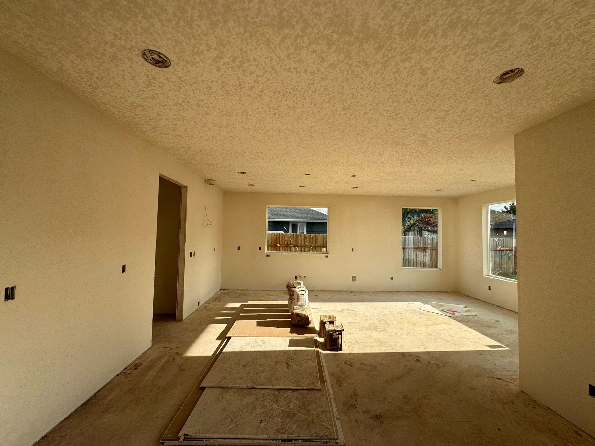 Interior of a room under construction with painted walls, bare floor, and recessed lighting.
