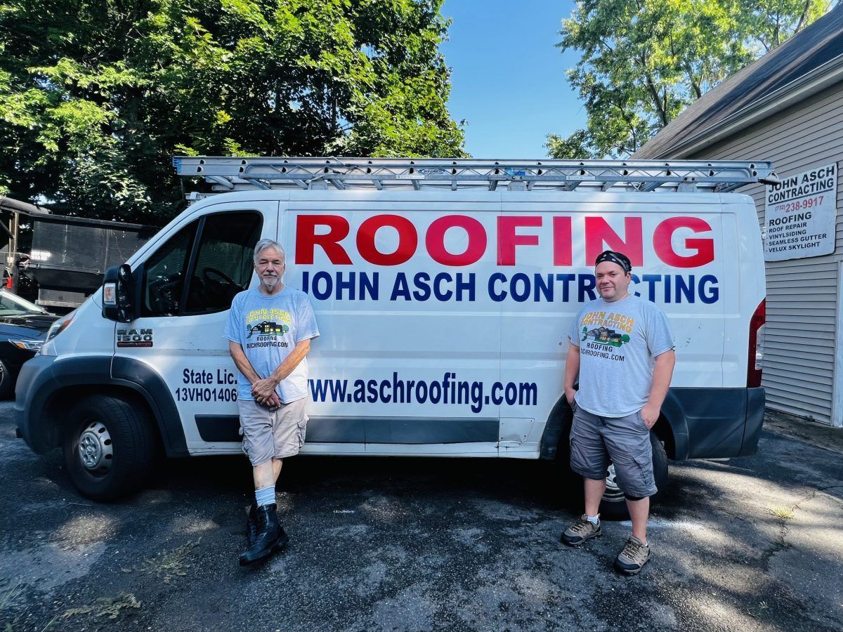 Two men standing beside a roofing company van. The van says ROOFING JOHN ASCH CONTRACTING.