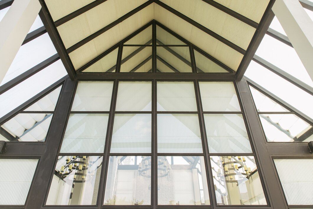 Triangular glass ceiling with black framing in a building.