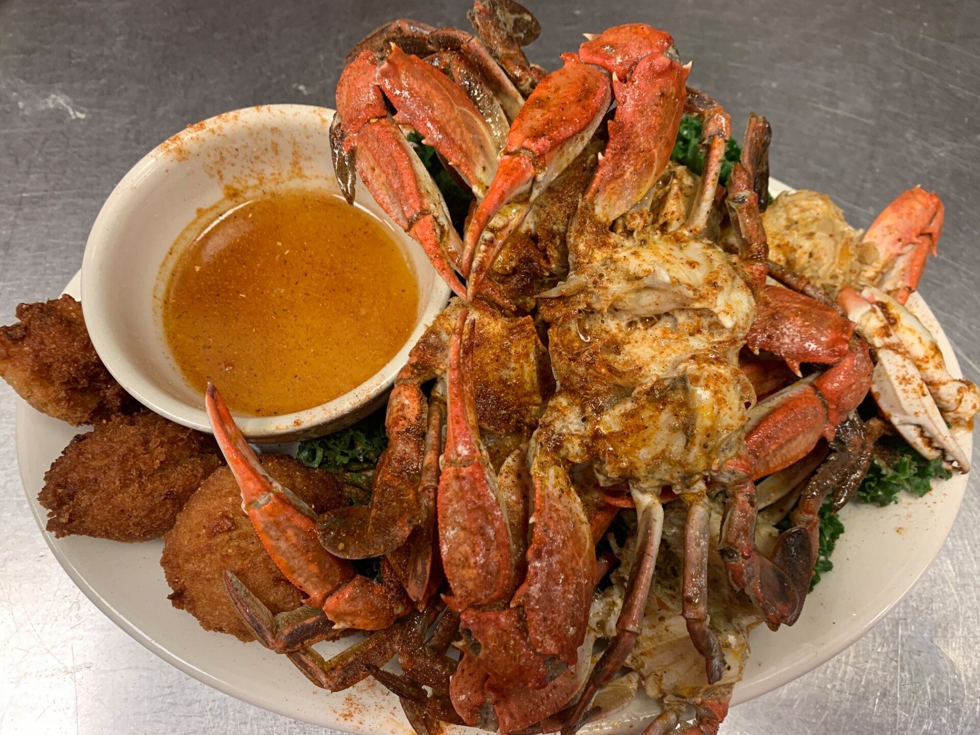 A plate of crabs and shrimp with a dipping sauce on a table.