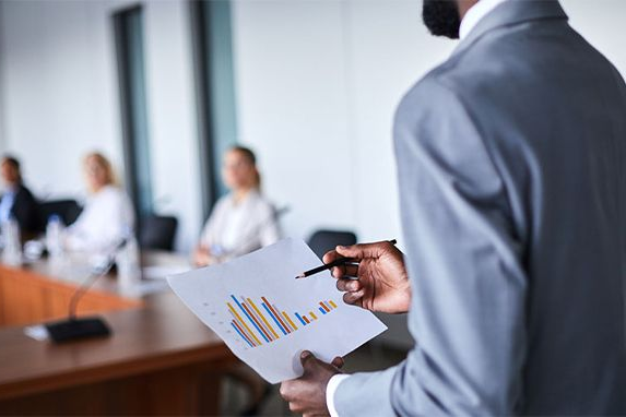 Man in suit presenting financial data to colleagues in a boardroom.