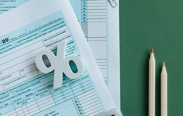 Tax forms with a percentage sign and two pencils.