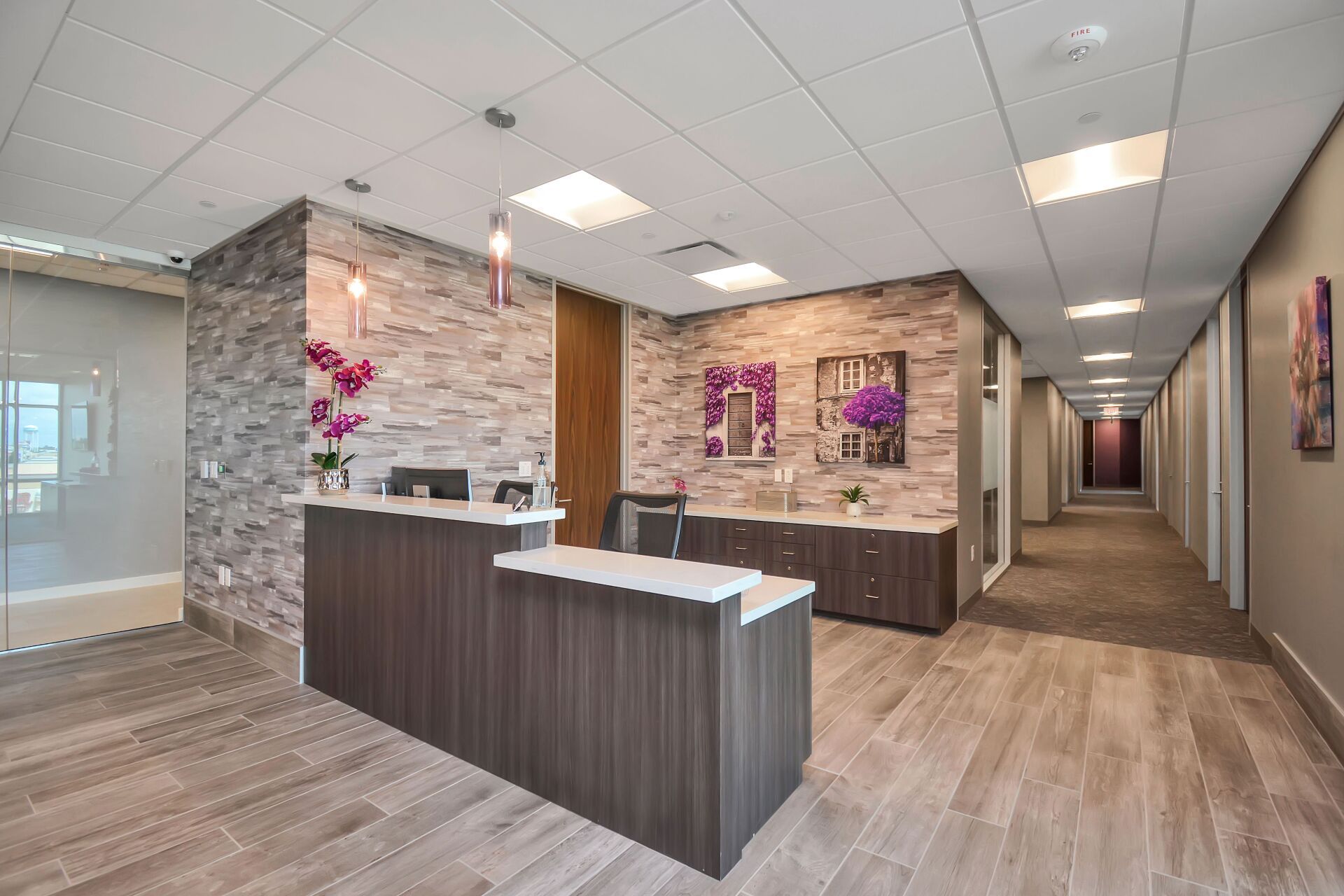 A long hallway with a reception desk in the middle of it.