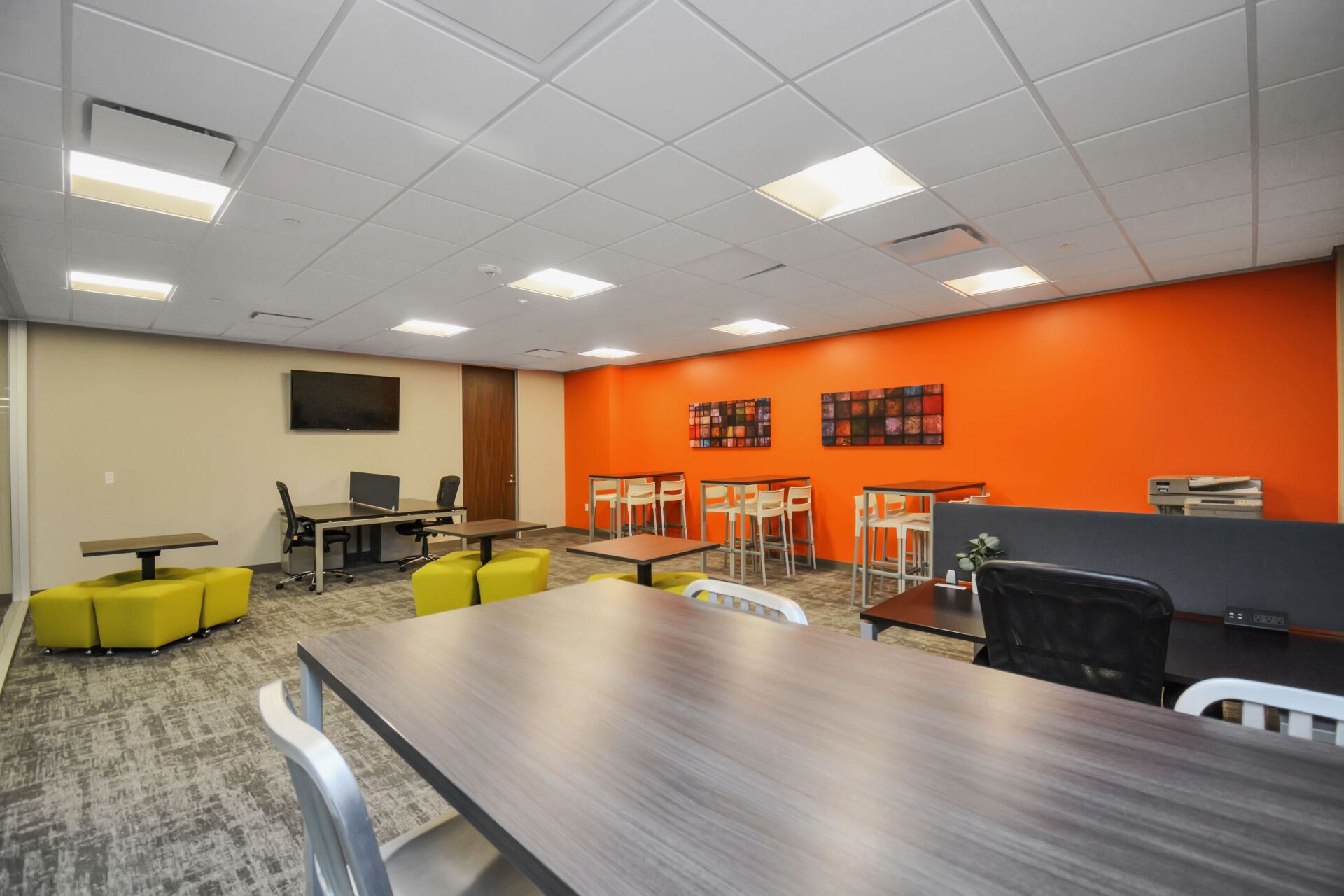 A large room with tables and chairs and orange walls.