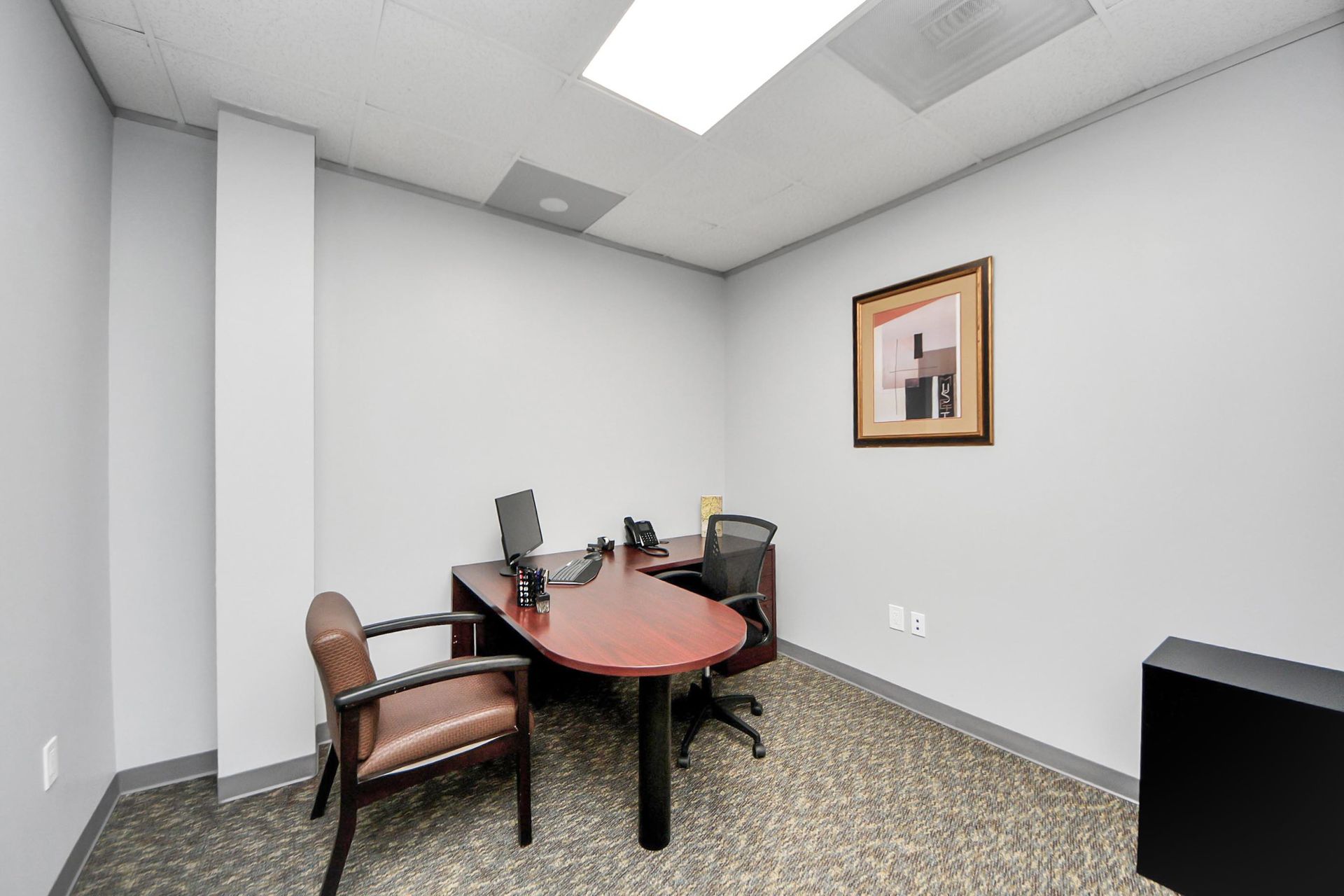 A small office with a desk and chairs in it.