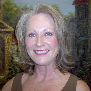 A woman is smiling in front of a painting.