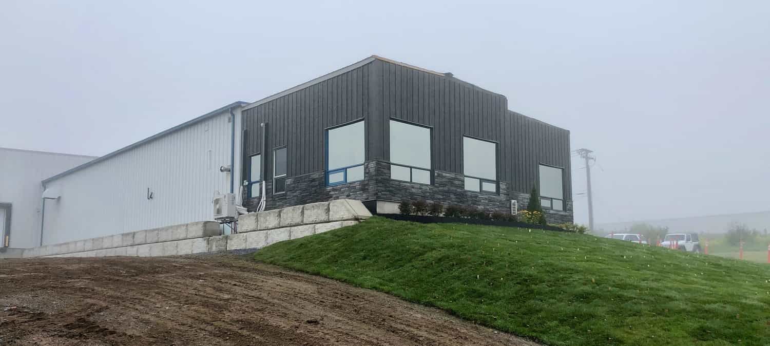 A large building is sitting on top of a grassy hill.