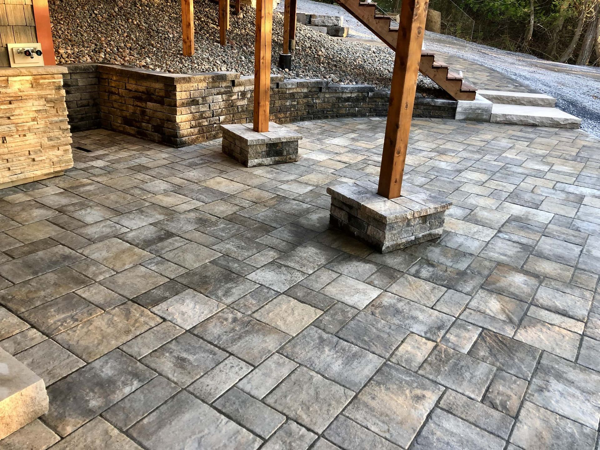 A patio with a wooden staircase and a stone wall.