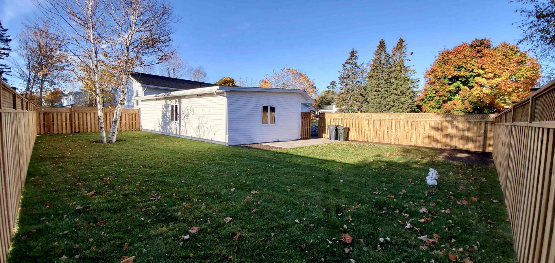 The backyard of a house with a wooden fence and a white house.