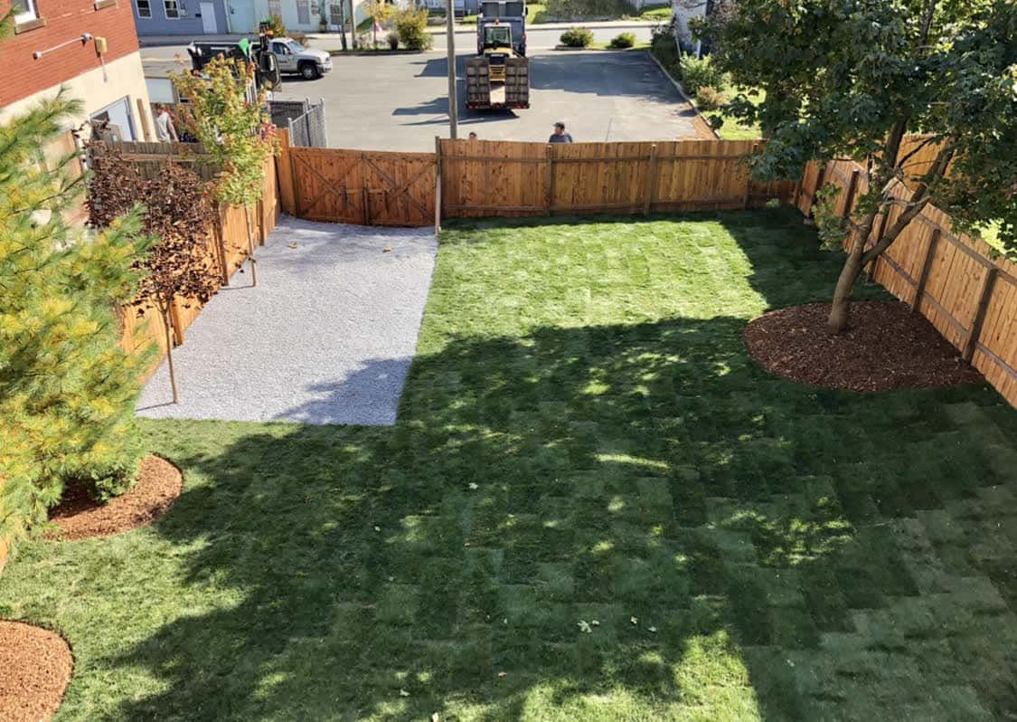 An aerial view of a backyard with a wooden fence and a lush green lawn.