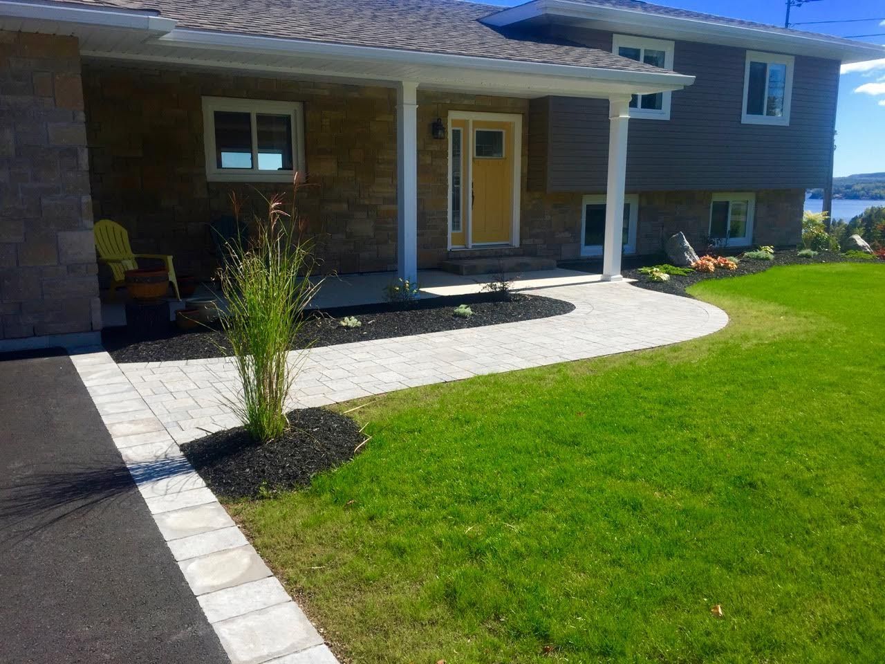 A large house with a lush green lawn and a walkway leading to the front door.