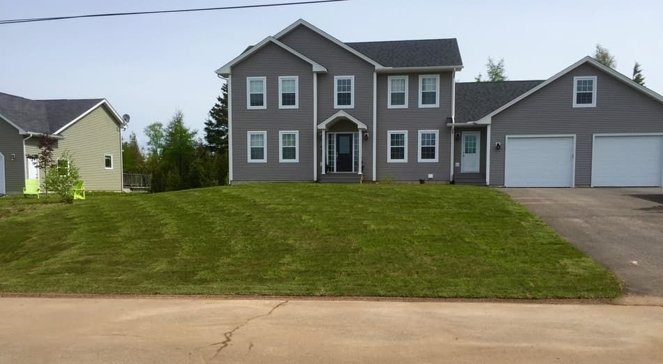 A large house with two garages and a large lawn in front of it.