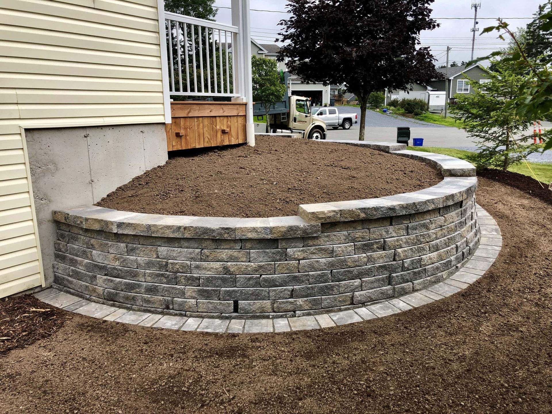 A brick wall is surrounded by dirt in front of a house.