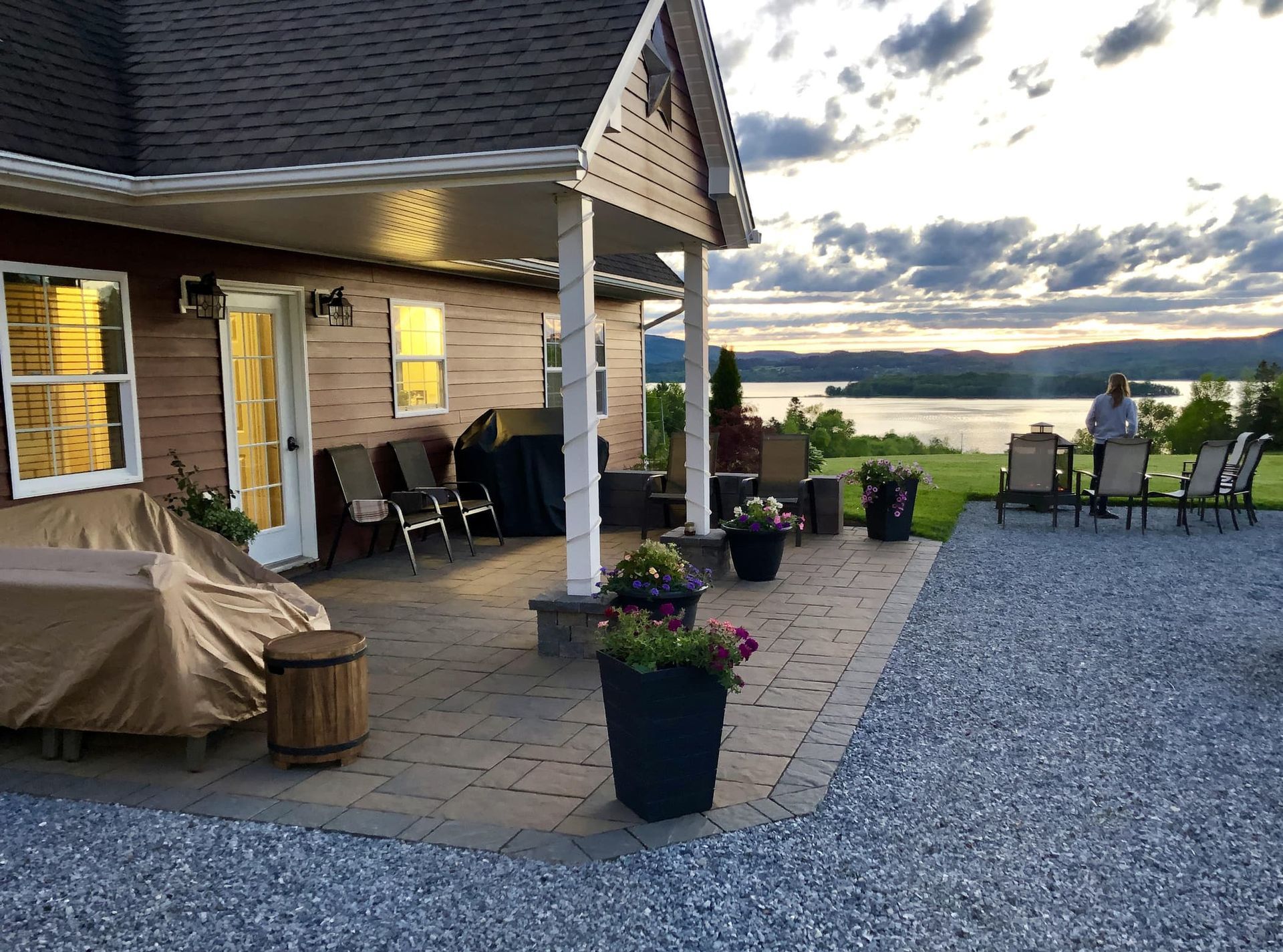 A patio with a table and chairs in front of a house with a view of a lake.