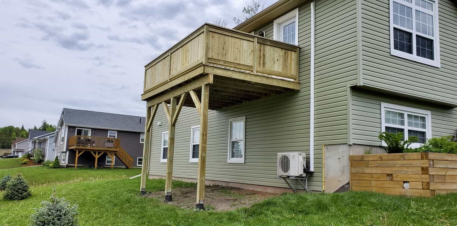 A house with a wooden deck on the side of it.
