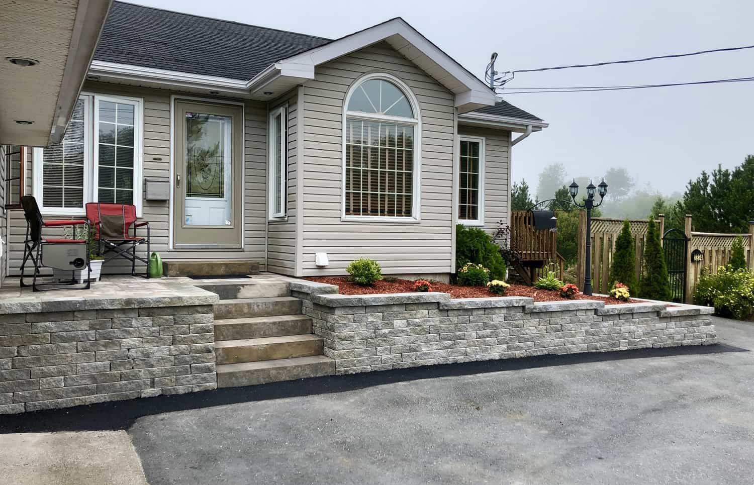 A house with a stone wall and stairs in front of it.