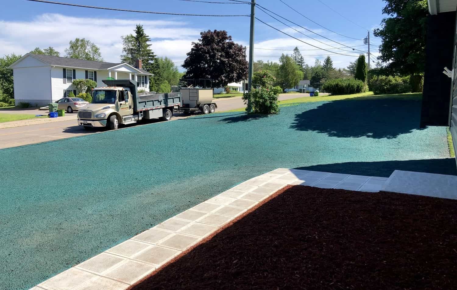 A dump truck is parked on the side of the road next to a house.