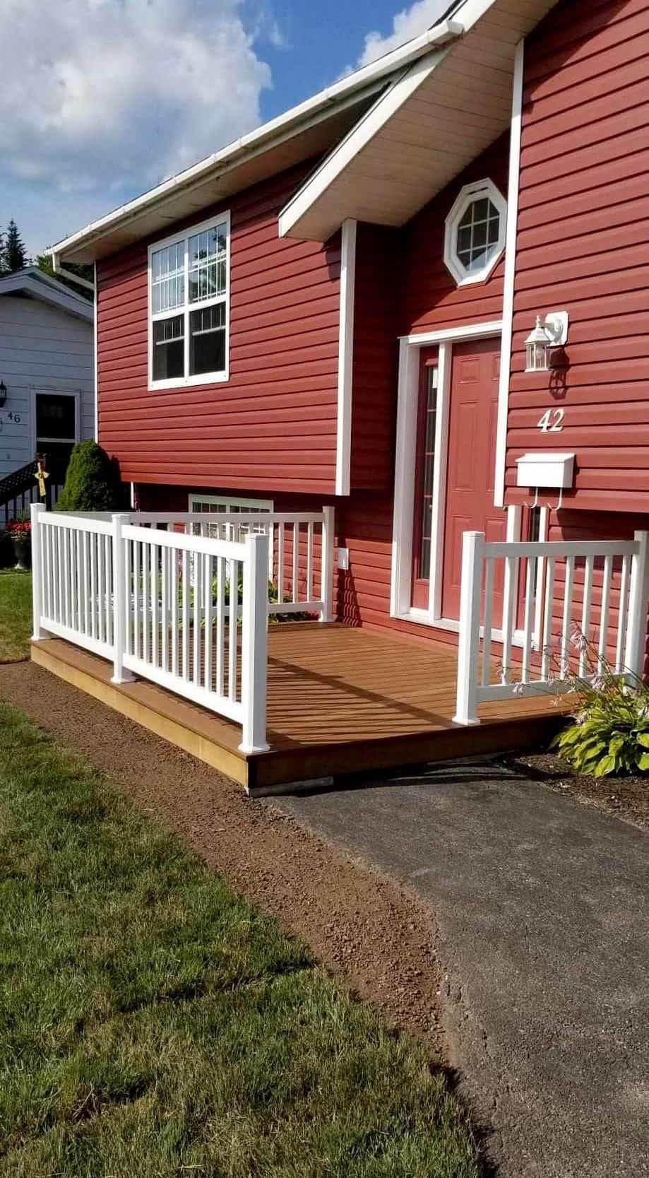 A red house with a wooden deck and a white railing.