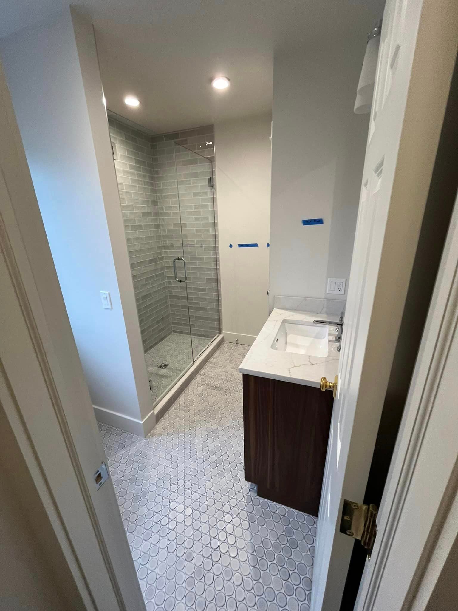 A bathroom with a sink and a walk in shower.