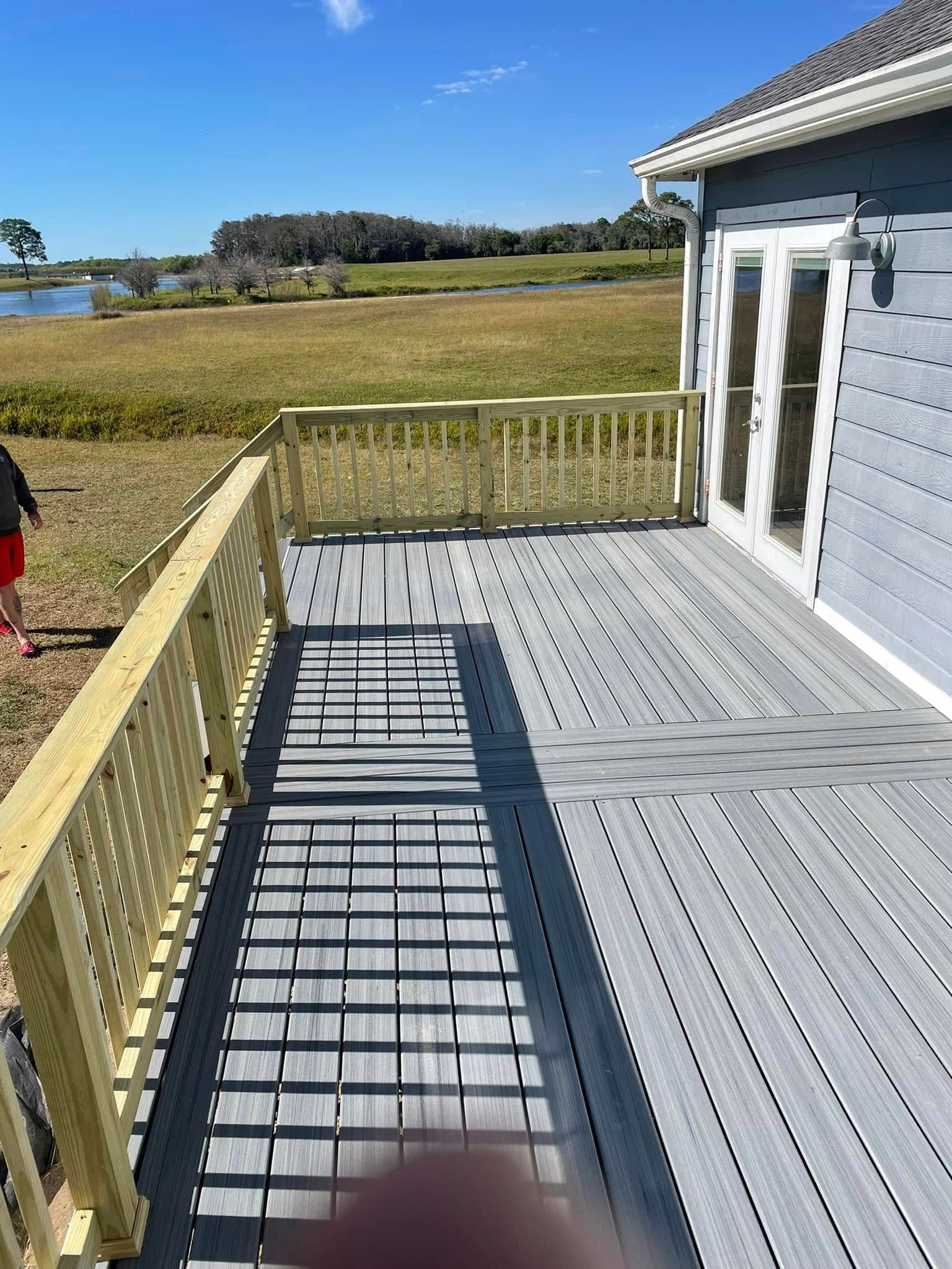 A person is standing on a wooden deck next to a house.
