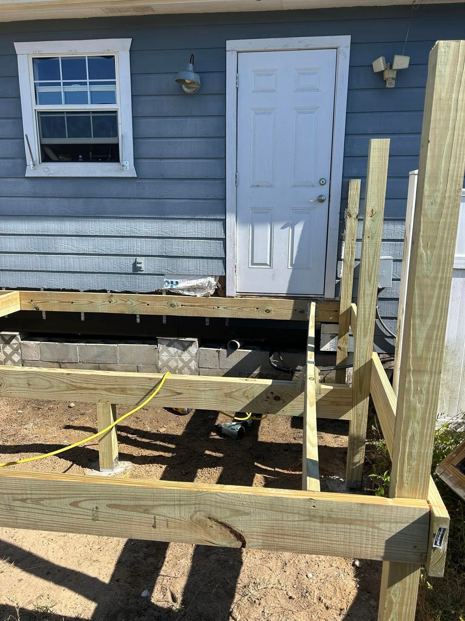 A wooden deck is being built in front of a house.