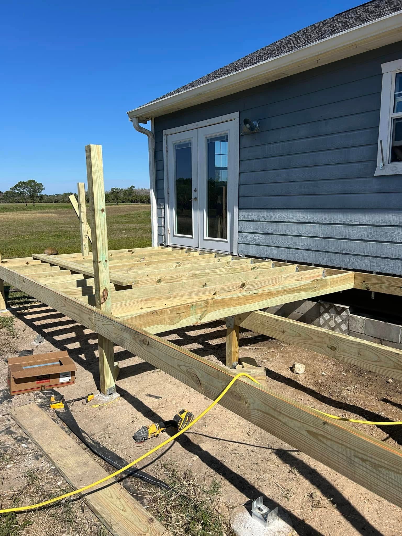 A wooden deck is being built in front of a house.