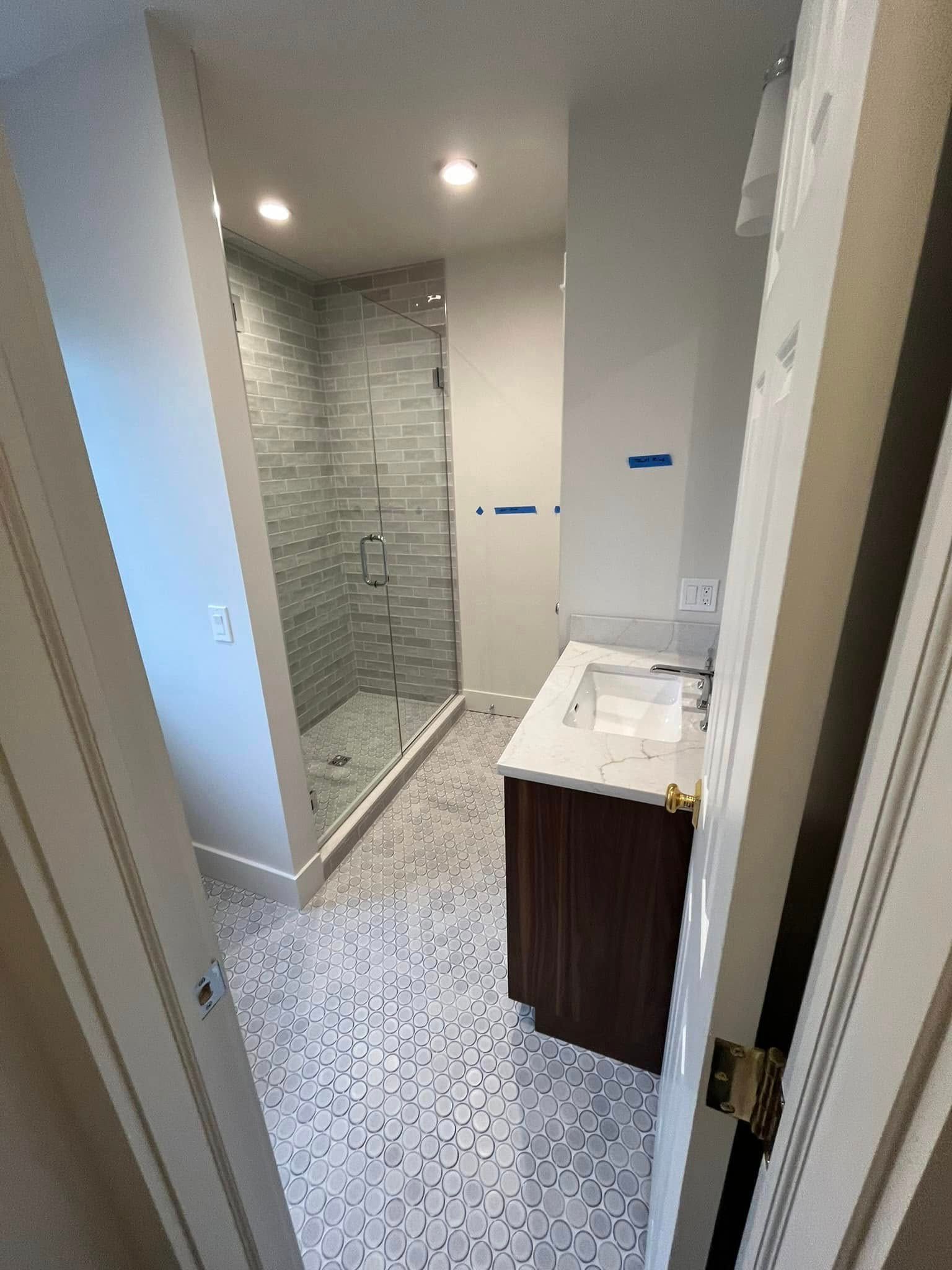 A bathroom with a sink and a walk in shower.