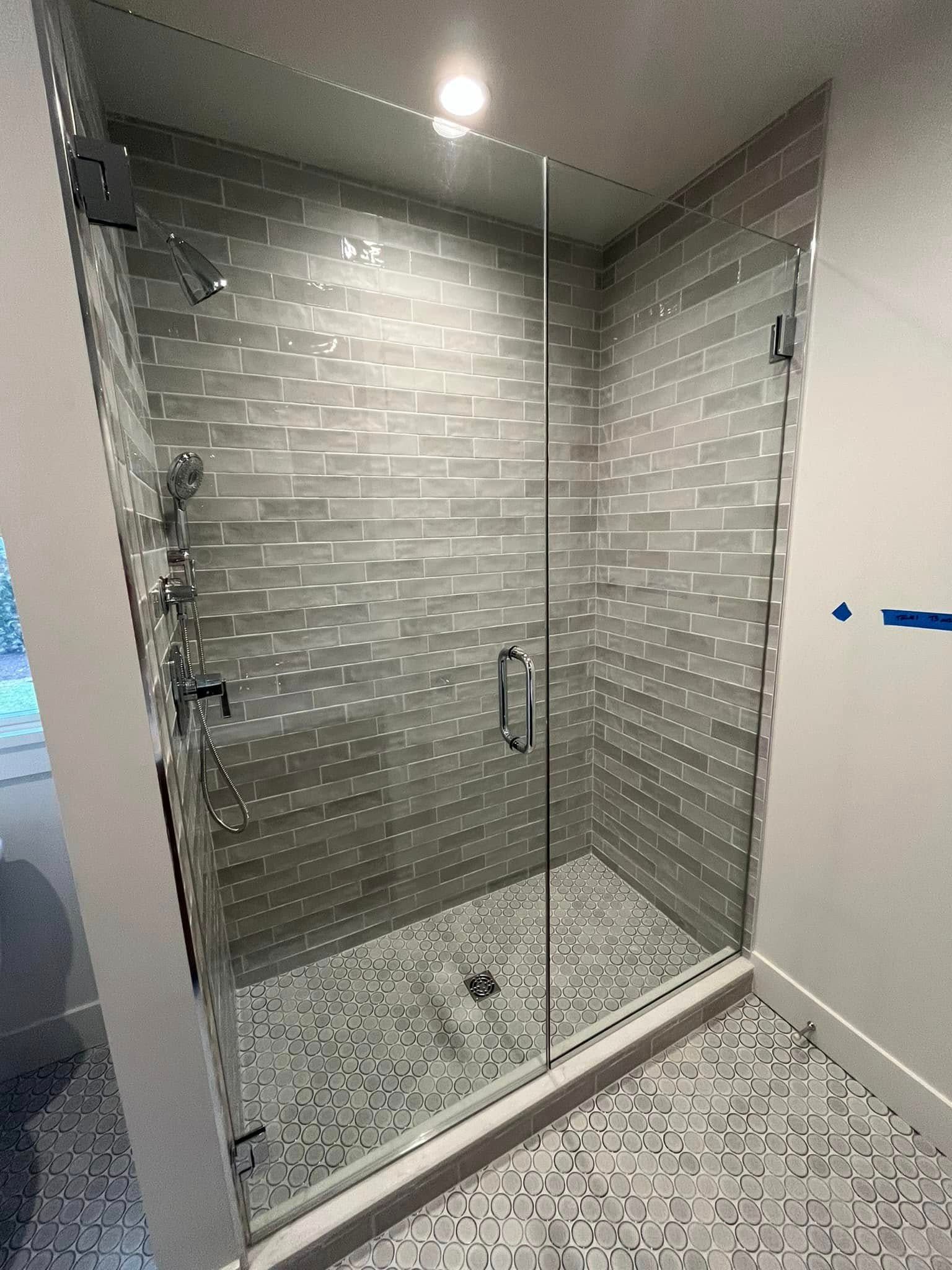 A bathroom with a walk in shower with a glass door.