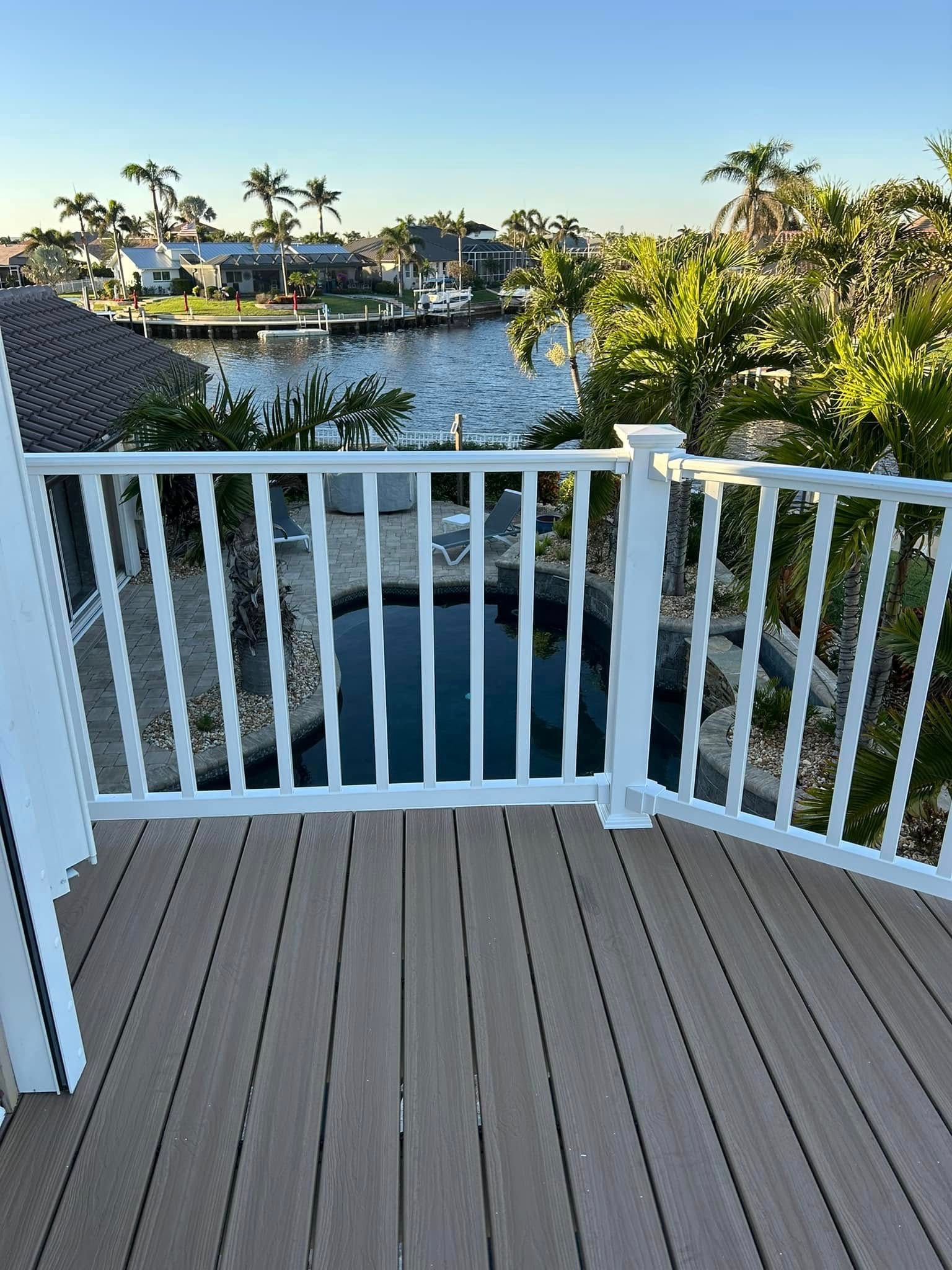 A deck with a white railing overlooking a body of water.