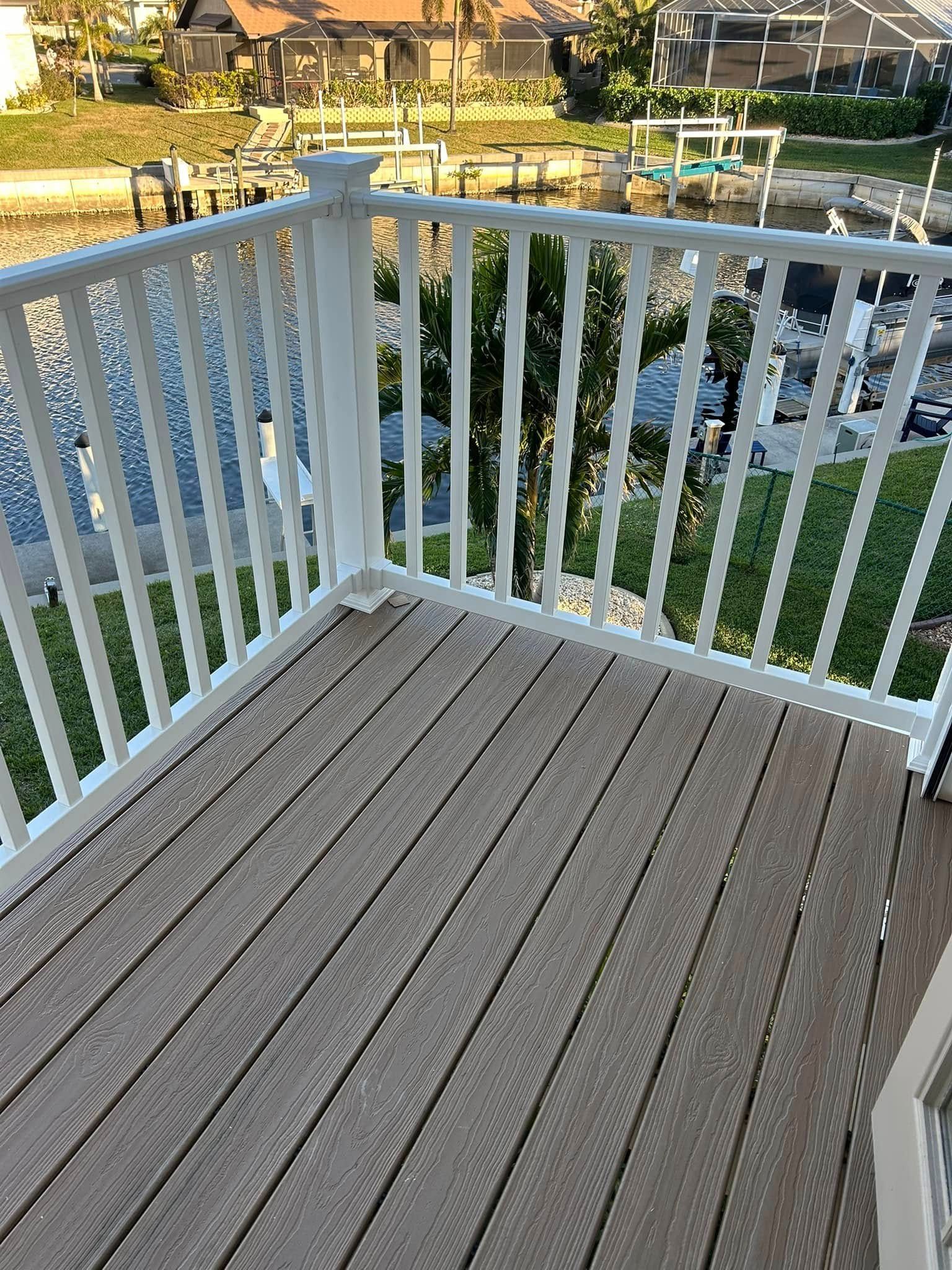 A wooden deck with a white railing overlooking a body of water.