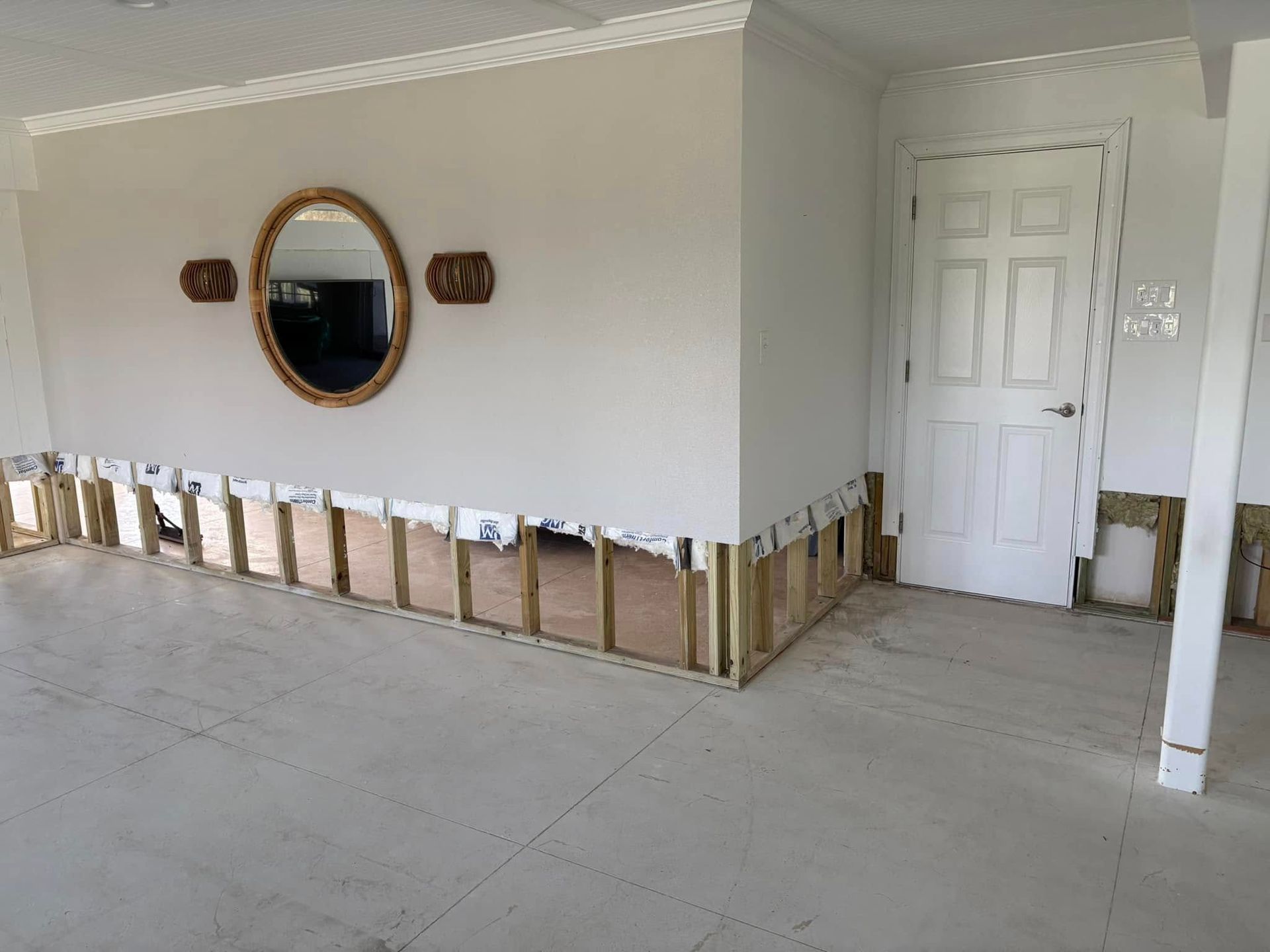 A living room with a mirror on the wall and a door.