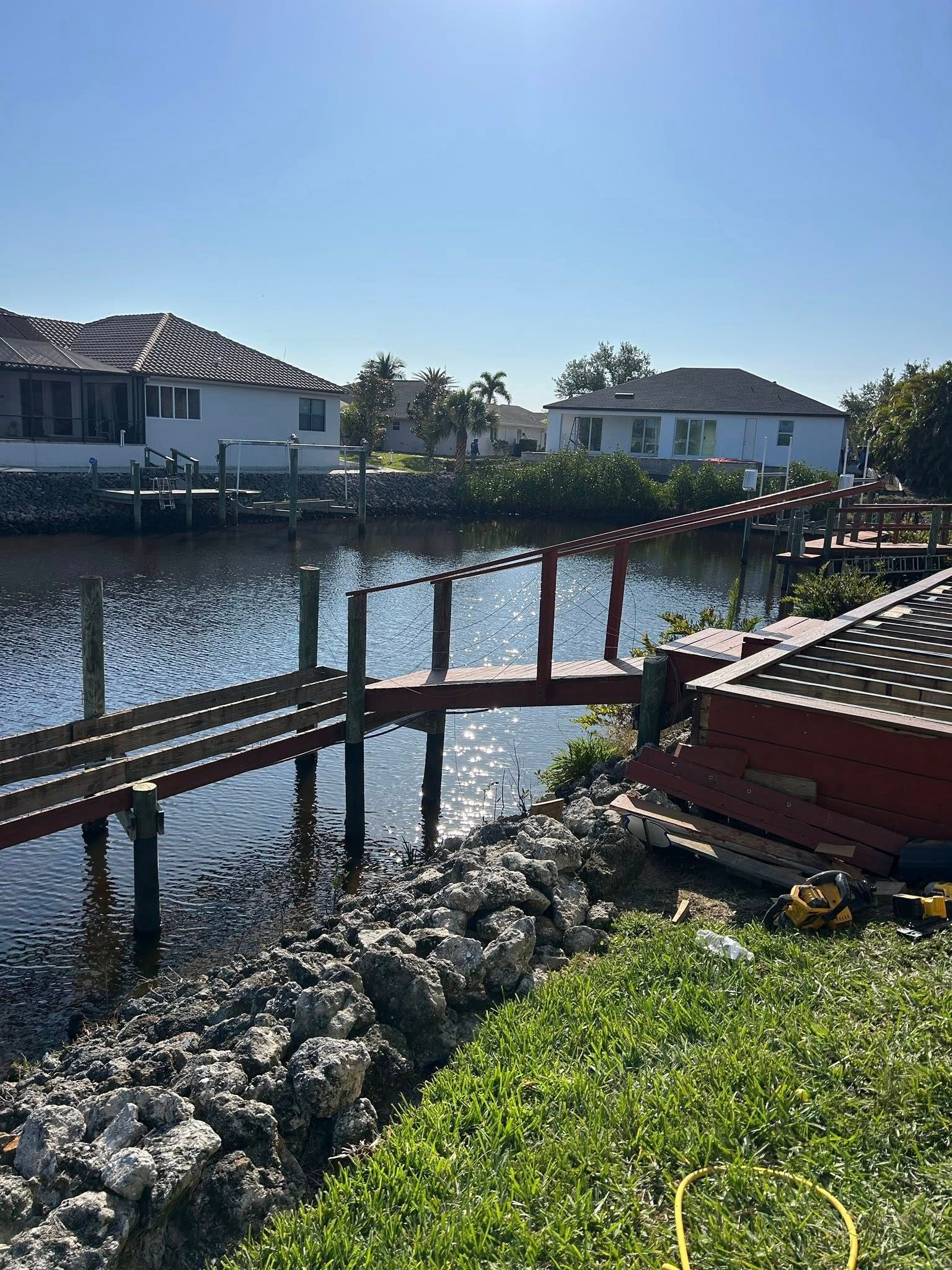 A wooden bridge over a body of water with houses in the background.