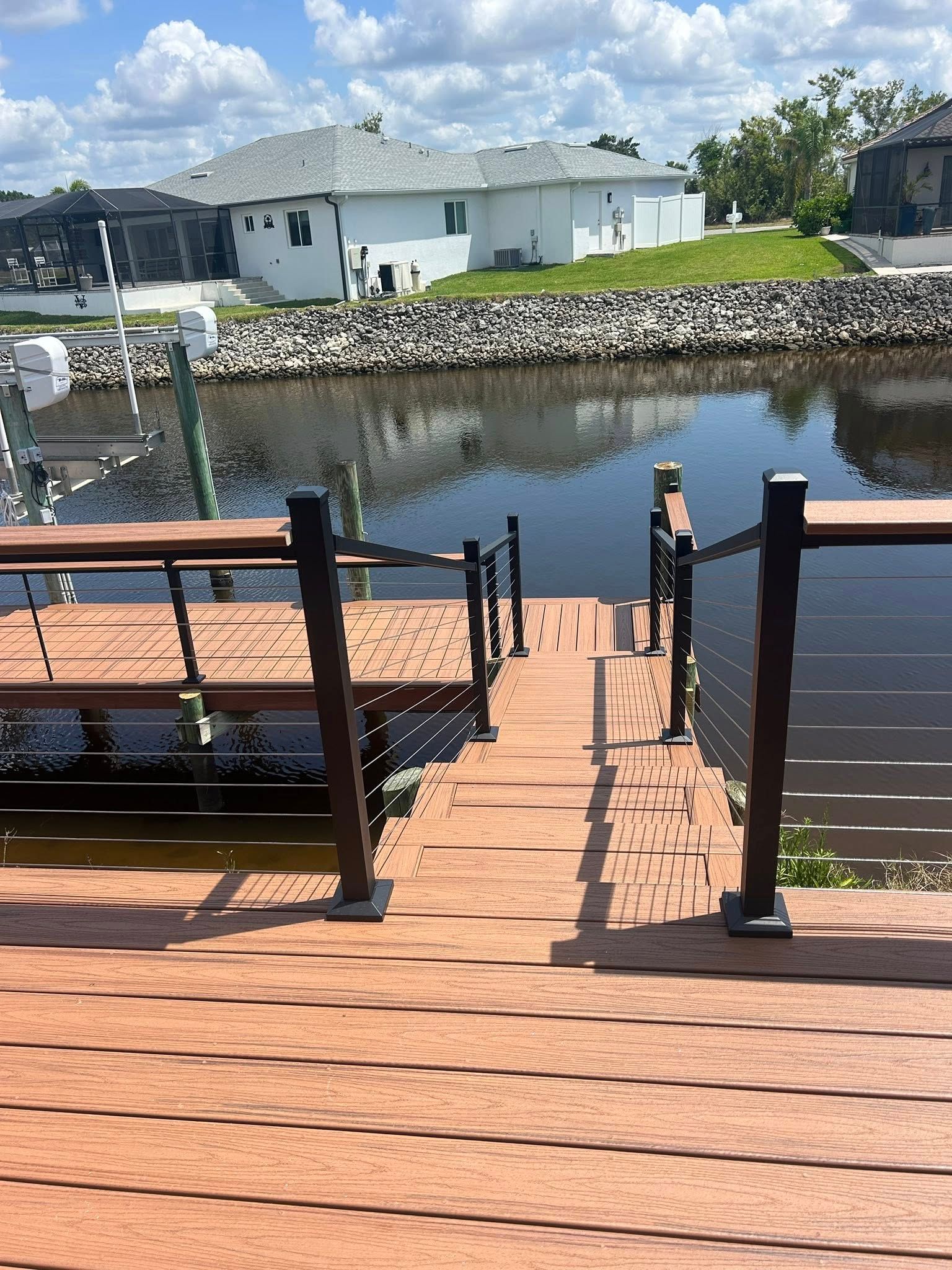 A wooden dock leading to a body of water with a house in the background